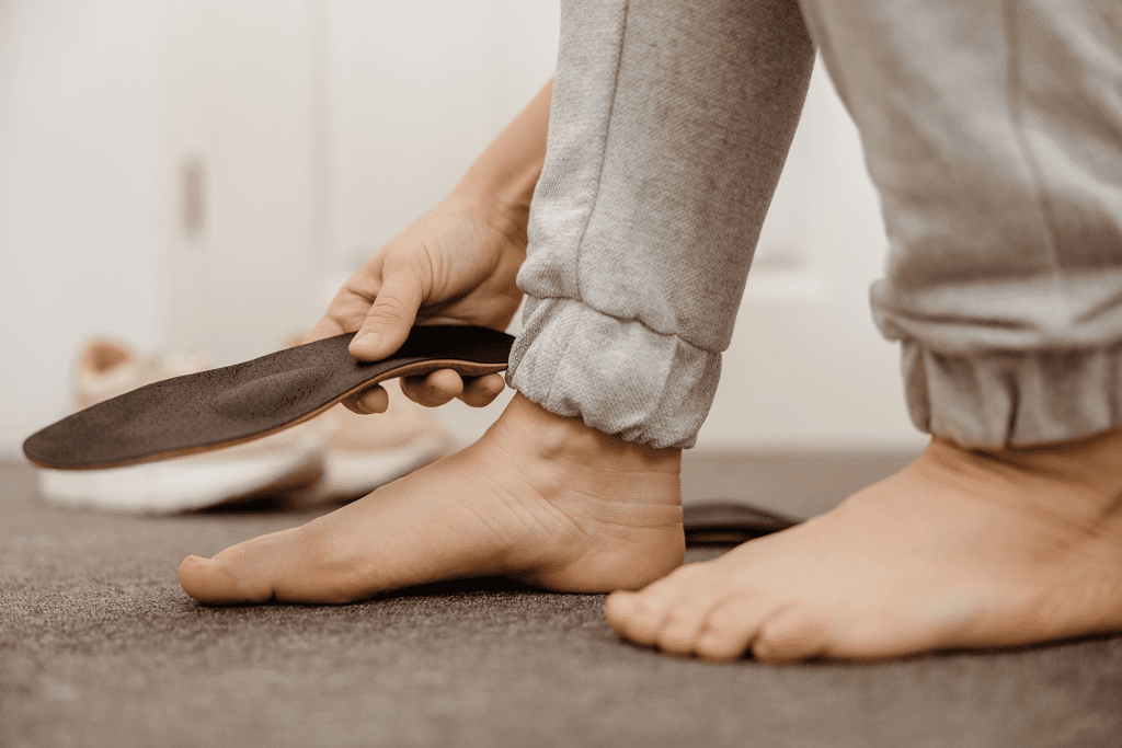 konservative Therapie bei Schmerzen im Fuß | Mann mit Plattfuß hält Einlage neben seinen Fuß
